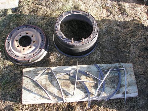 1990 Chevrolet Suburban - Two vehicle wheel rims and metal strips are displayed on the ground.