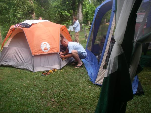 Two tents set up on grass with people around them