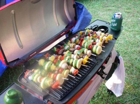 1978 Ford Bronco - A portable grill is cooking vegetable skewers outdoors, with a can of beer in a koozie on the side table.