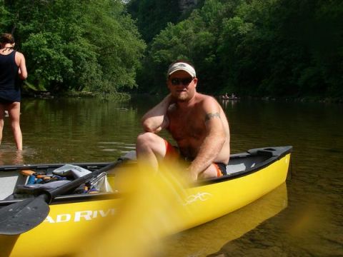 1978 Ford Bronco - A man relaxes in a canoe on a calm river surrounded by trees.