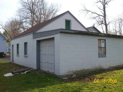 1995 Mercury Grand Marquis - A white cinder block garage with a single overhead door and two windows is shown on a sunny day.