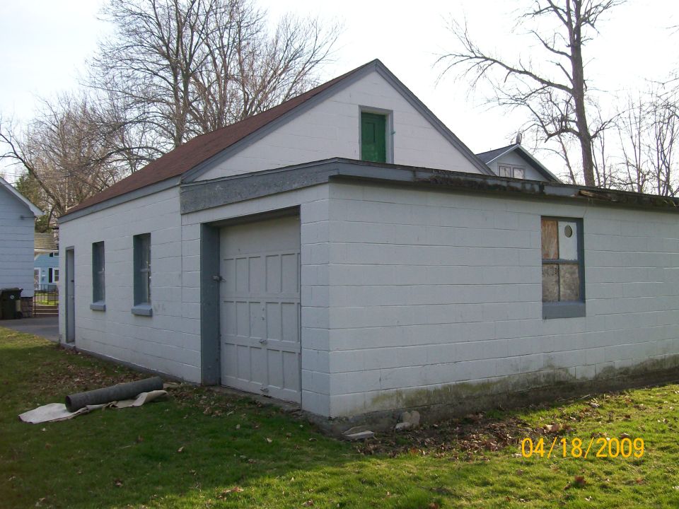 Exterior of a white cinder block garage with a single overhead door and two windows