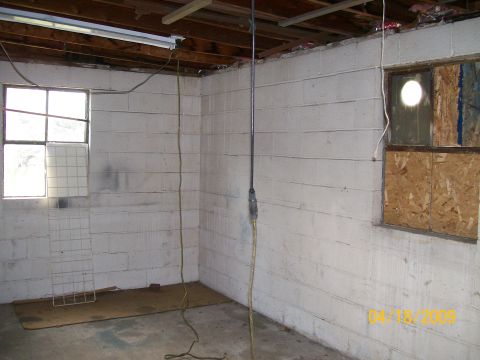 1995 Mercury Grand Marquis - Empty corner of a whitewashed cinder-block garage or shop with a bare concrete floor, exposed ceiling joists, a fluorescent fixture and a y…