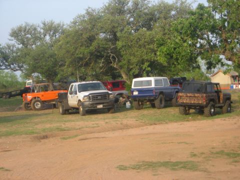 1979 Ford Bronco - A camouflaged Ford Bronco is parked outdoors with other vehicles and trees in the background.