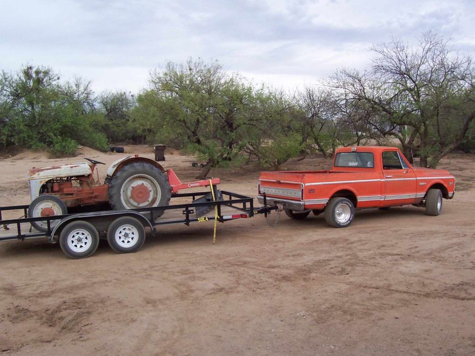 1972 Chevrolet C/K Pickup towing a trailer with a tractor