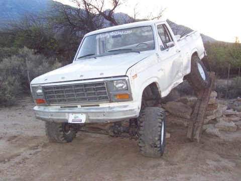 1981 Ford F-150 - This white Ford pickup truck, likely a 1979 model based on its grille, is navigating an obstacle course with its front wheels elevated.