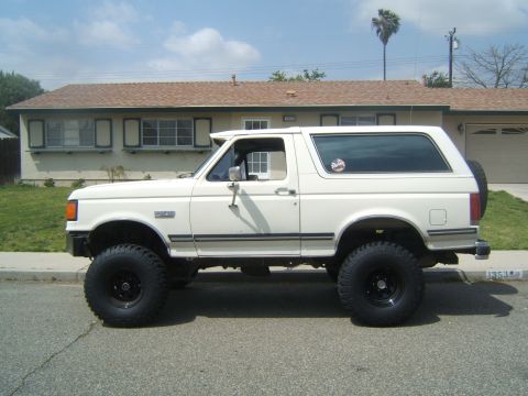 1988 Ford Bronco - Side view of a white Ford Bronco with aftermarket wheels and tires.