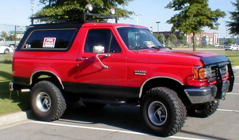 1983 Ford Bronco - This red Ford Bronco has a roof rack and a bull bar, with a "FOR SALE" sticker on the window.