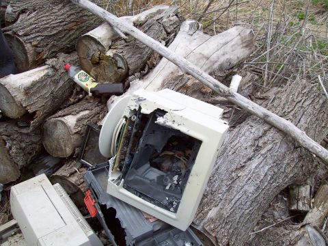 2000 Mercury Grand Marquis - Discarded electronics and logs are piled together outdoors.