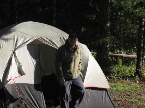 1979 Ford Bronco - A man stands in front of a large tent at a wooded campsite.