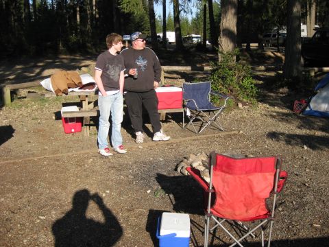 1979 Ford Bronco - A campsite scene with two men, camping chairs, coolers, and a tent set up in a wooded area.