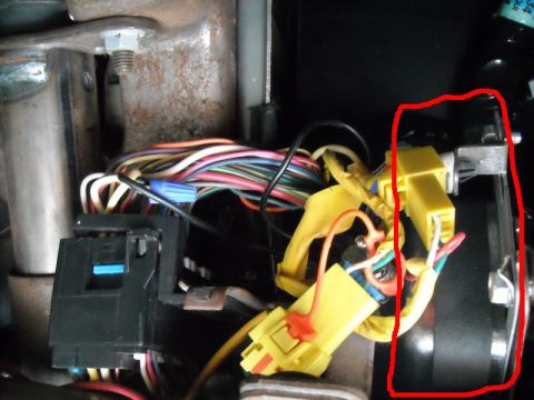 2000 Chevrolet Tahoe - A complex wiring harness with numerous colorful wires and connectors is visible, with a red circle drawn around a metal component.
