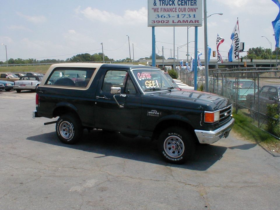 Dark green 1987-91 Ford Bronco with tan top at a used car and truck dealer lot
