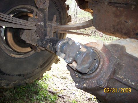 1978 Ford Bronco - Close-up view of the rear axle and suspension system of a vehicle, showing signs of rust and wear.