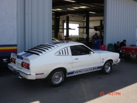 1978 Ford Mustang II - White 1978 Ford Mustang II Cobra II with blue stripes parked outside a garage.