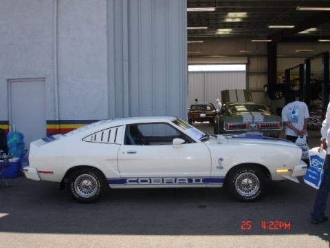 1978 Ford Mustang II - A white 1978 Ford Mustang II Cobra II is parked outside a garage, with other vehicles visible inside.