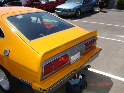 1978 Ford Mustang II - Rear view of a yellow 1978 Ford Mustang II hatchback, with a blue Ford Mustang in the background.