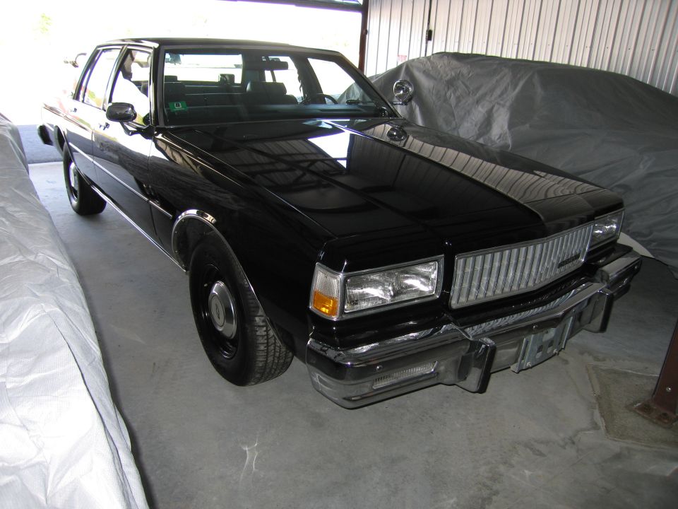 Black sedan with a chrome grille and rectangular headlights, parked indoors