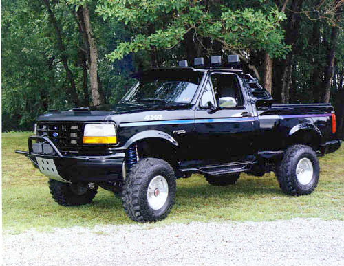 Lifted black 1992-96 Ford Bronco on large tires with roof light bar and tube bumper