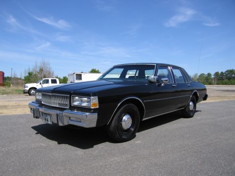 1991 Ford LTD Crown Victoria - Black sedan with chrome grille and trim, parked outdoors with a white pickup truck behind it.