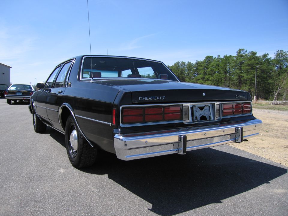 Black Chevrolet Caprice sedan parked on asphalt, another car in background