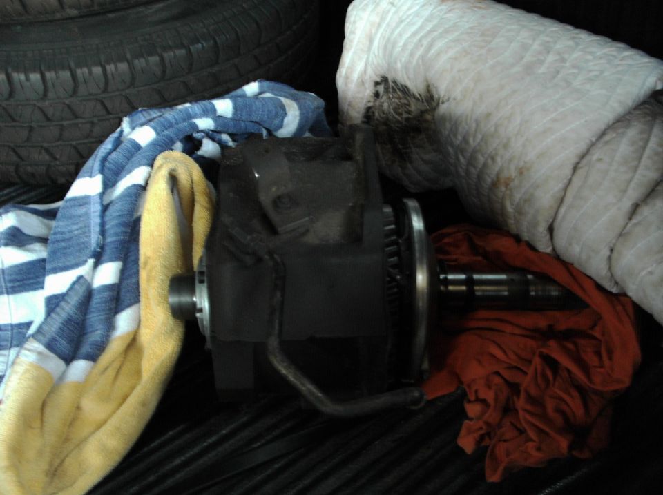Black automotive part with gears and shaft, covered by towels and cloth