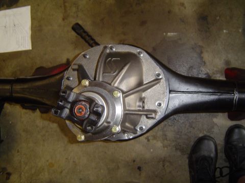 1989 Ford Bronco - A rear axle differential assembly is shown, with a U-joint connected to the pinion yoke. A technical diagram is visible in the background.