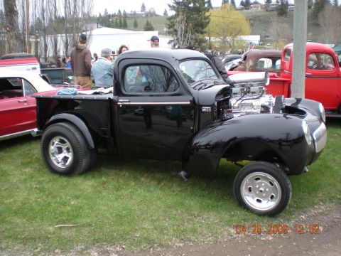 1974 Ford Ranchero - A custom black pickup truck with a powerful engine is displayed outdoors next to other vehicles.