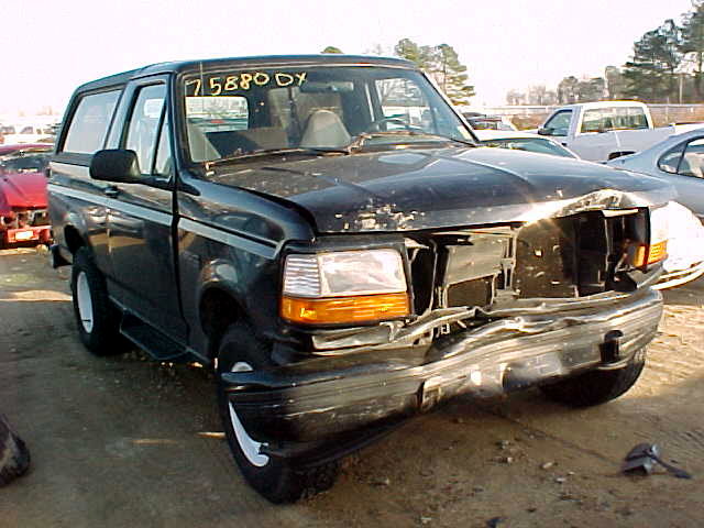Black Ford Bronco SUV with severe front-end crash damage in a salvage yard.