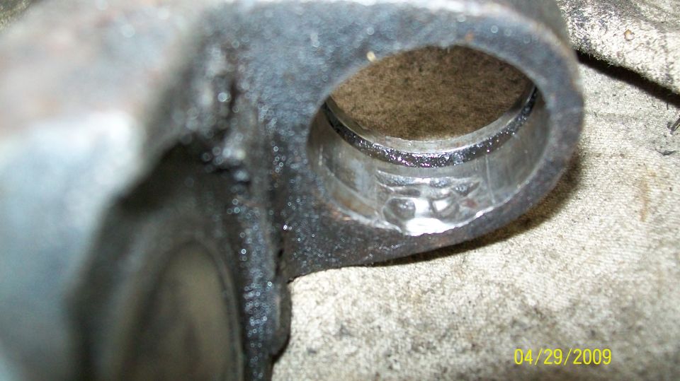 Close-up of a damaged U-joint with visible wear marks inside the bearing race