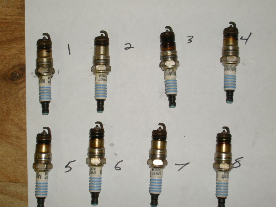 Eight spark plugs numbered 1-8, some showing wear