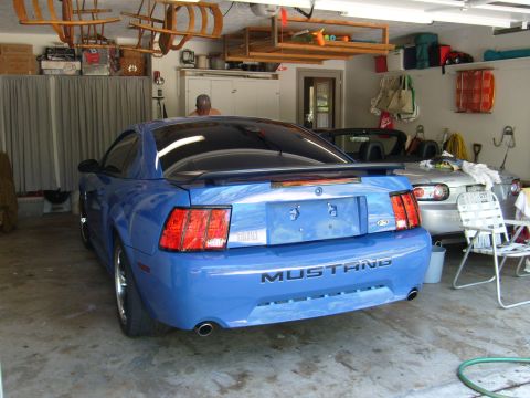 1992 Ford Bronco - A blue Ford Mustang is parked in a garage next to a silver convertible, with sleds overhead.