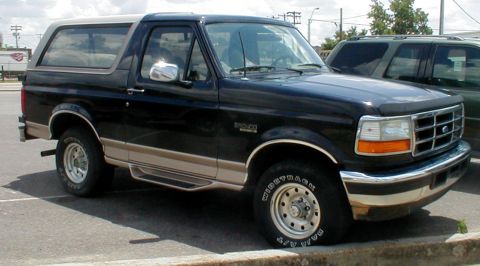 1983 Ford Bronco - This black Ford Bronco features tan two-tone trim and a chrome bumper, seen here from a 3/4 front angle.