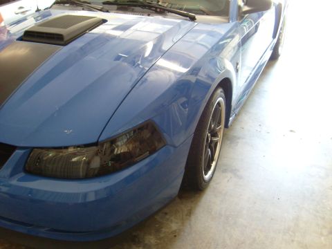 1992 Ford Bronco - Front view of a blue Ford Mustang, showing the headlight, fender, and hood scoop detail.