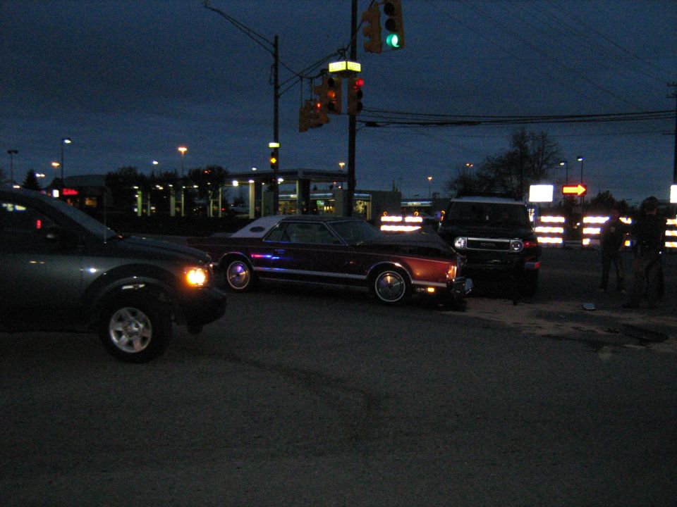 Maroon coupe with white vinyl roof, side view, at dusk