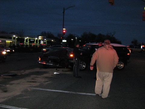 1988 Mercury Grand Marquis - Two vehicles, a black sedan and a white SUV, are at a gas station during dusk, with people standing around them.