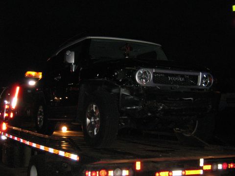 1988 Mercury Grand Marquis - A black Toyota FJ Cruiser is loaded onto a flatbed truck at night, showing front-end damage.