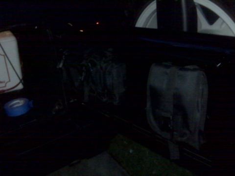 2008 Jeep Wrangler - The interior cargo area of a vehicle contains several bags and a roll of blue tape.