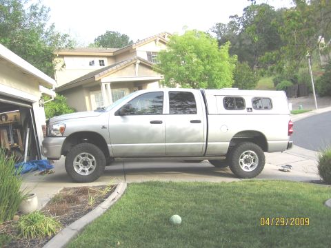 2007 Dodge 2500 - Side view of a silver pickup truck with a camper shell, parked in a residential driveway.