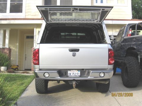 2007 Dodge 2500 - A silver Dodge Ram pickup truck is parked next to another vehicle, with its camper shell open.