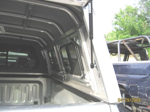 2007 Dodge 2500 - Interior view of a truck bed camper shell, showing windows and support struts. Another vehicle is partially visible in the background.