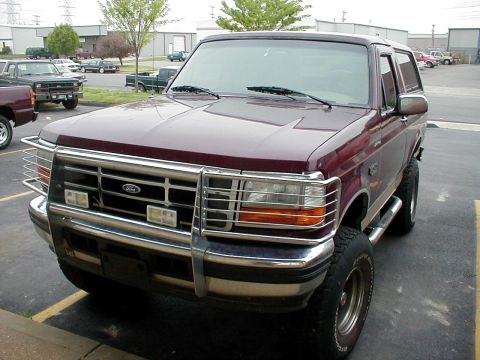 1983 Ford Bronco - This maroon SUV, likely a 1992 Ford Bronco, is equipped with a prominent chrome bull bar and side steps.
