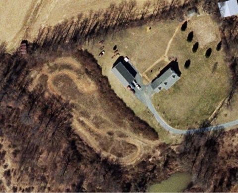 1948 Jeep Wrangler - An aerial perspective captures a rural landscape a winding dirt track and several structures.