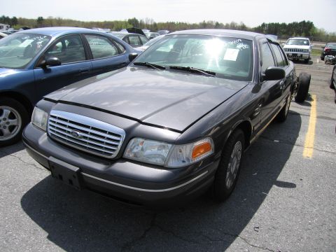 2001 Ford Crown Victoria - This 2001 Ford Crown Victoria is seen from the front-three-quarter view with its hood open and missing a front wheel.