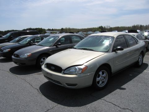 2001 Ford Crown Victoria - Several sedans are parked in an outdoor lot under a bright sky.