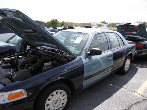 2001 Ford Crown Victoria - A two-tone 2001 Ford Crown Victoria is seen with its hood open in a vehicle lot.