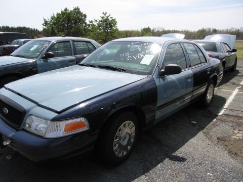 2001 Ford Crown Victoria - This 2001 Ford Crown Victoria is seen in a lot with other vehicles, one with its hood open.