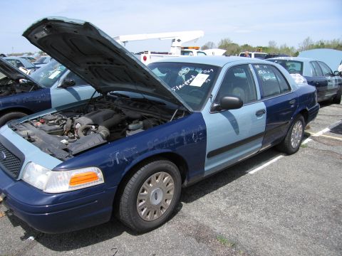 2001 Ford Crown Victoria - Two-tone blue 2001 Ford Crown Victoria with hood open, parked next to another similar vehicle.