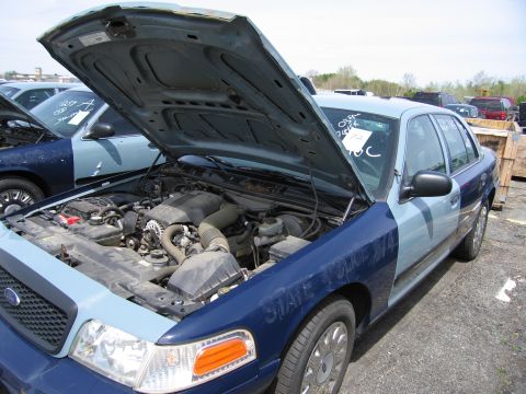 2001 Ford Crown Victoria - Engine bay of a 2001 Ford Crown Victoria, parked in an outdoor lot with other vehicles.