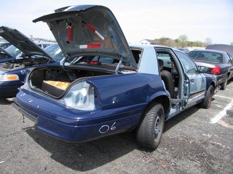 2001 Ford Crown Victoria - A blue Ford Crown Victoria sits in a lot with its trunk and driver's side door open, revealing its interior and trunk space.